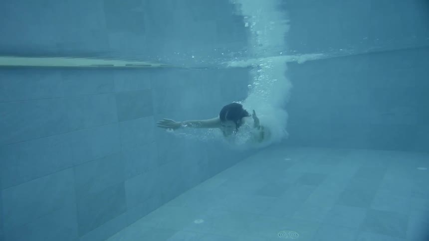 Woman enters pool swimming underwater then surfaces