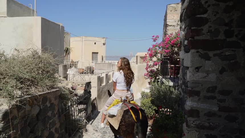 Woman rides donkey through narrow alley