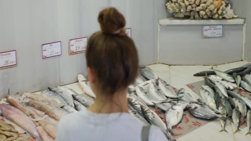 A woman checks out the types of fish at a fish market