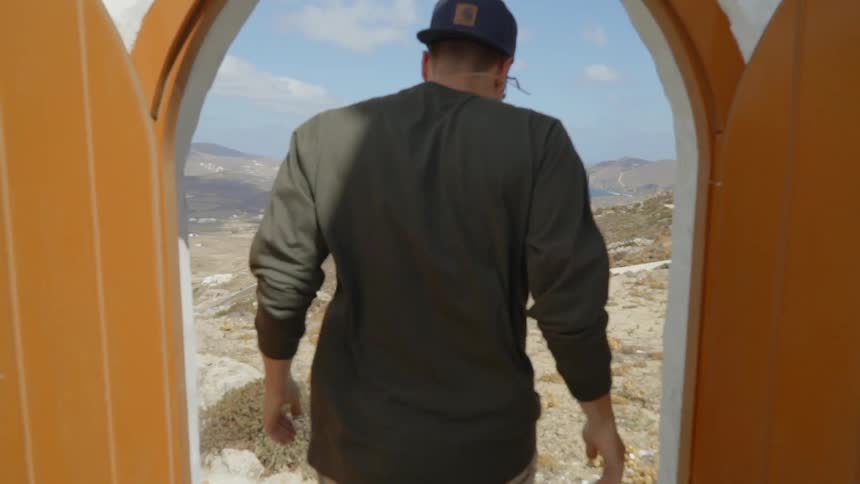A young man opens wooden doors and steps outside into the wind
