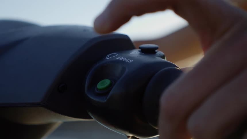 Outdoors during the day hand on handlebar presses start button