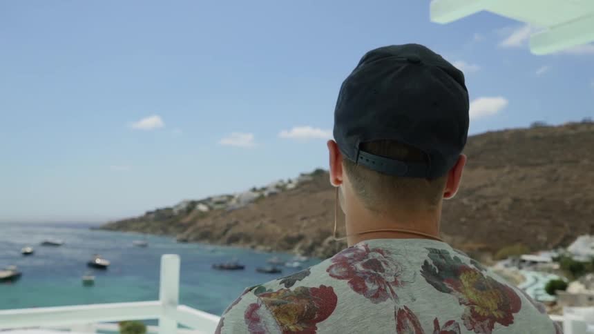 A man walks on a deck to look at the sea