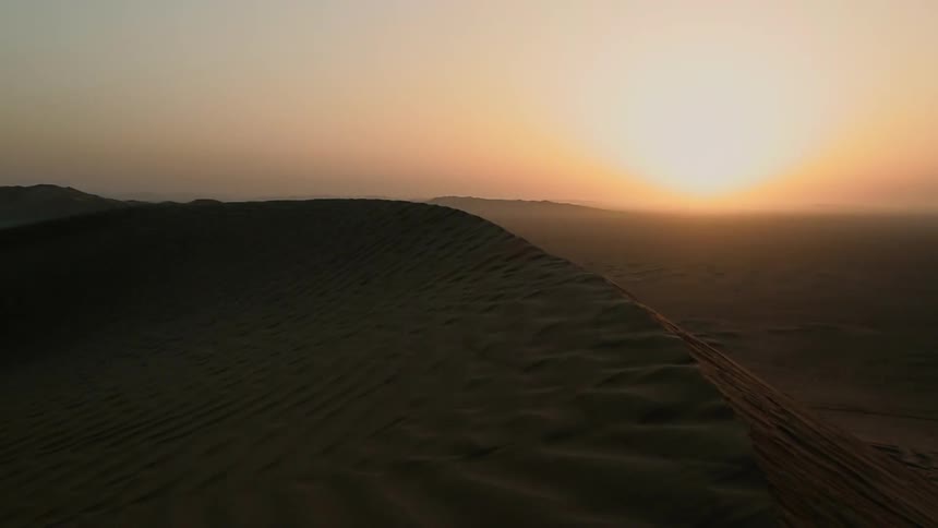 The sun is setting over the sand dunes