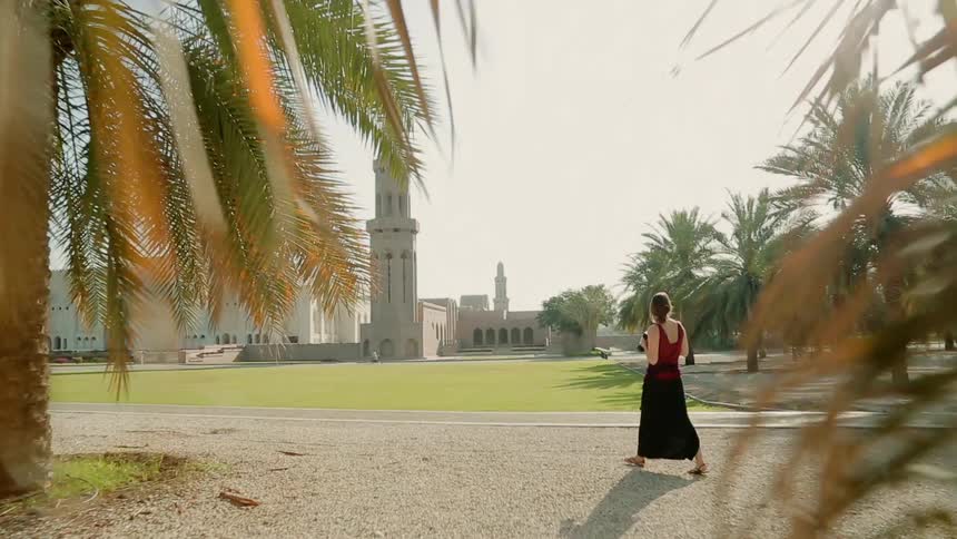 A woman walks towards a large church while carrying a camera