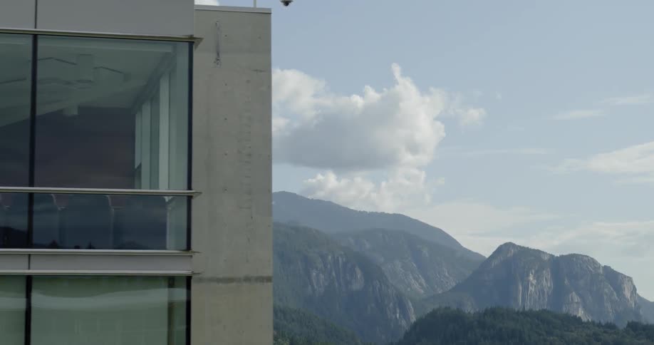 Tall building sits near the mountains on a sunny day