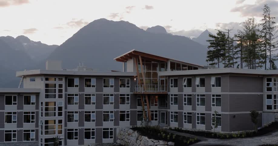Close up view of a large apartment building in front of the mountains