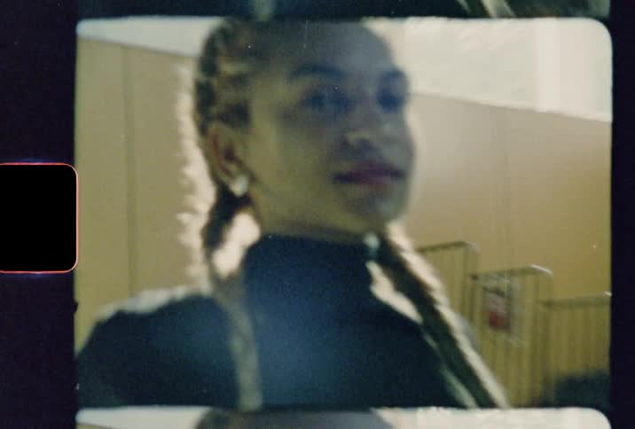 A woman is being video taped while sitting on a chair in a room