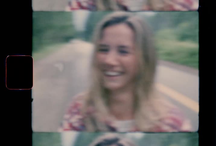 A woman laughs and smiles while standing in the road next to a pickup truck