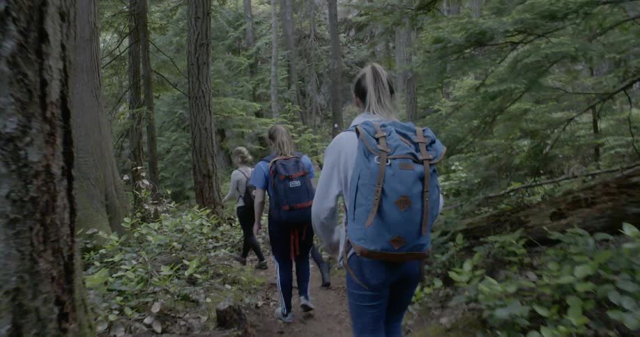 Teenage girls pick up the pace as they hike through a forest