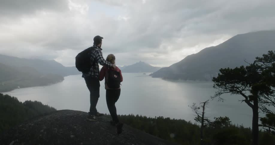 A man grabs his girlfriends hand to pull her into a hill during a hike