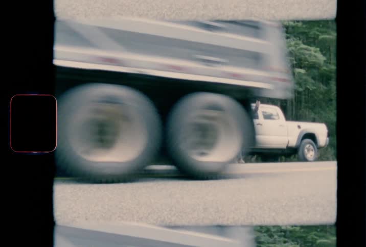 Two women stand near truck at side of road trying to wave semi down