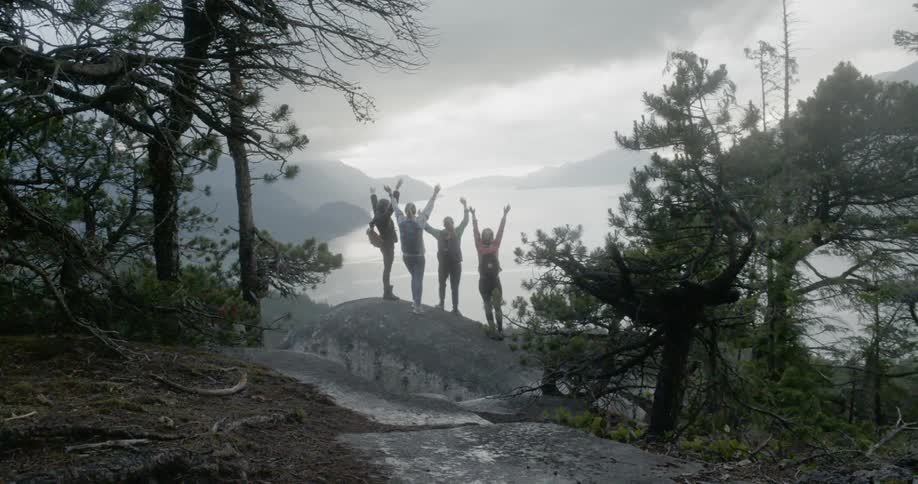 Girls celebrating on a rock overlooking a lake in the mountains