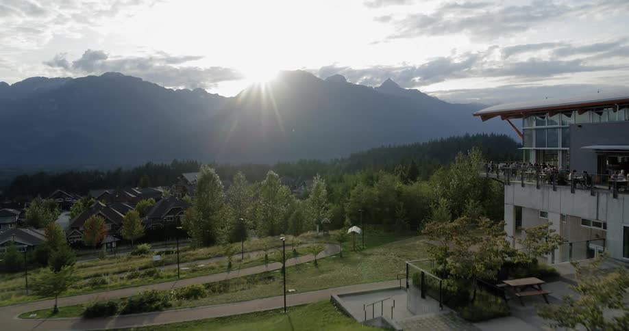 The sun shines over hills onto the rooftops of homes surrounded by trees