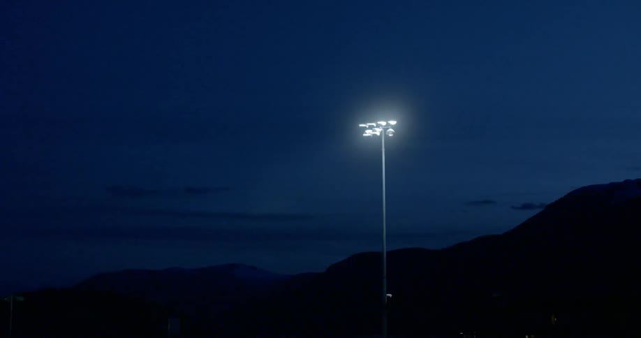 A street light at dark with mountains and the sky in the background