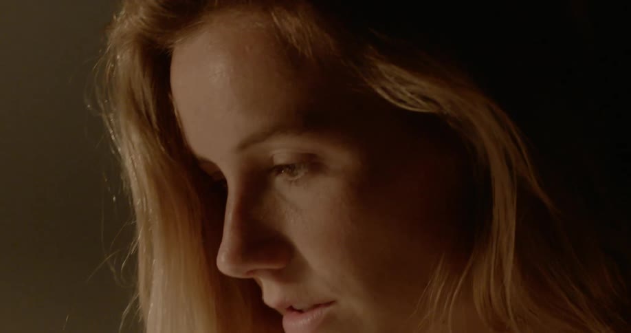 Blonde woman looks down and talks to herself in the room