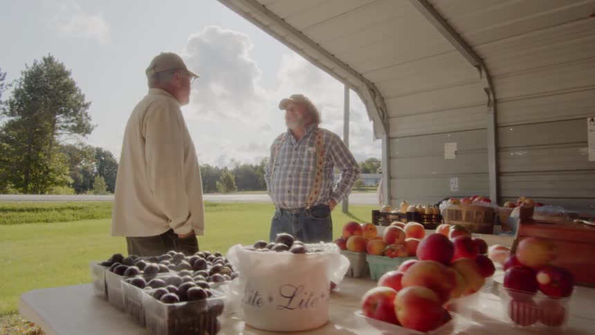 Two men talk at a farmer market