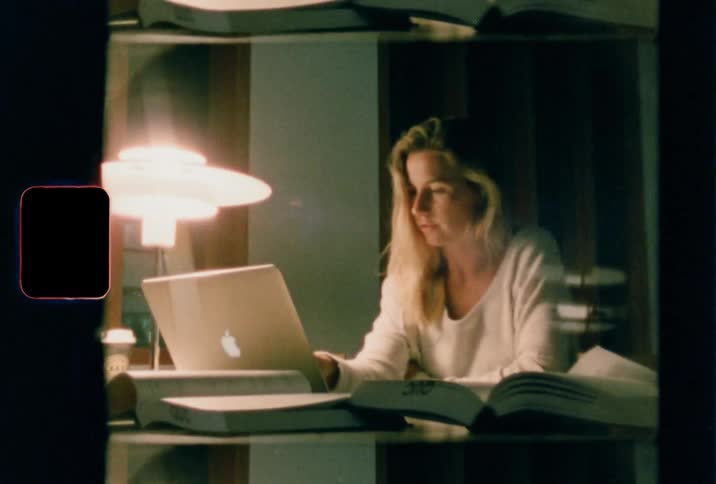 Woman sitting at the desk uses a laptop in a dark room