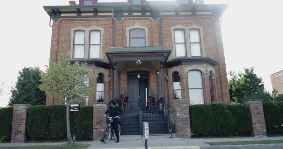 A black girl gets ready to ride a bike in front of a house