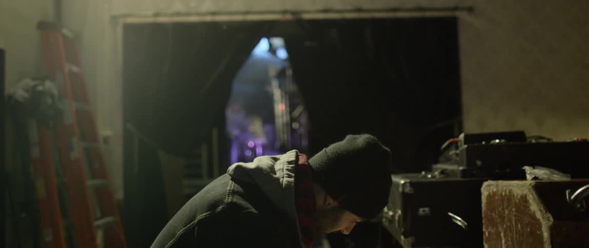A man backstage tuning a guitar