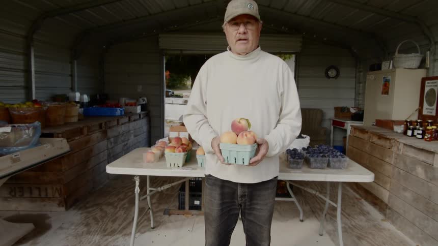 Man standing in front of a table holding a basket of fruit