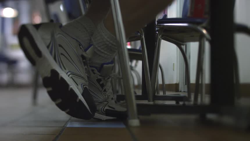 Kid with ankles crossed sits at desk