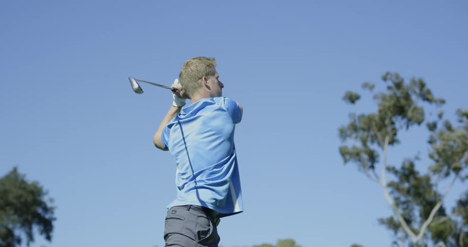 Male golfer taking a swing with golf club outdoors