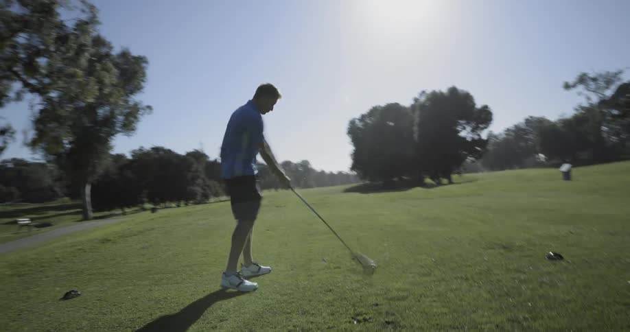 Male golfer hitting golf ball with a driver at a golf course