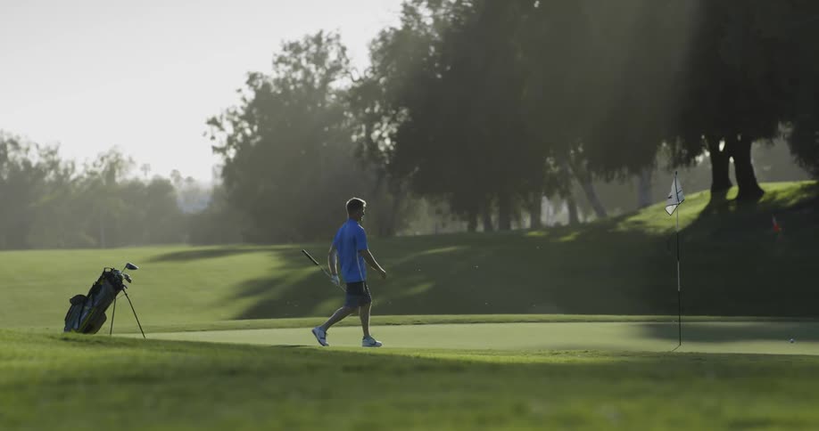 Man sets golf bag down and removes flag from hole