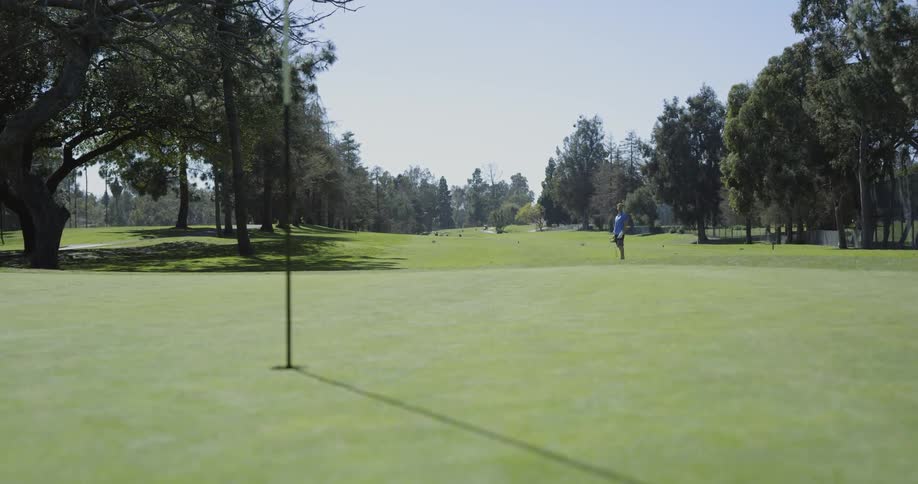 A man swings his golf club on a golf course
