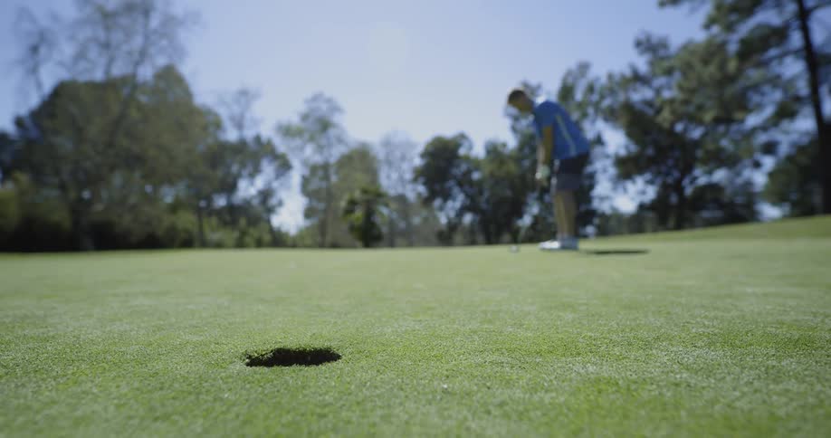 A man hits the ball toward the hole