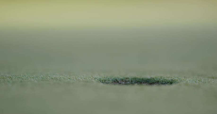 Close up of a golf ball rolling into the hole