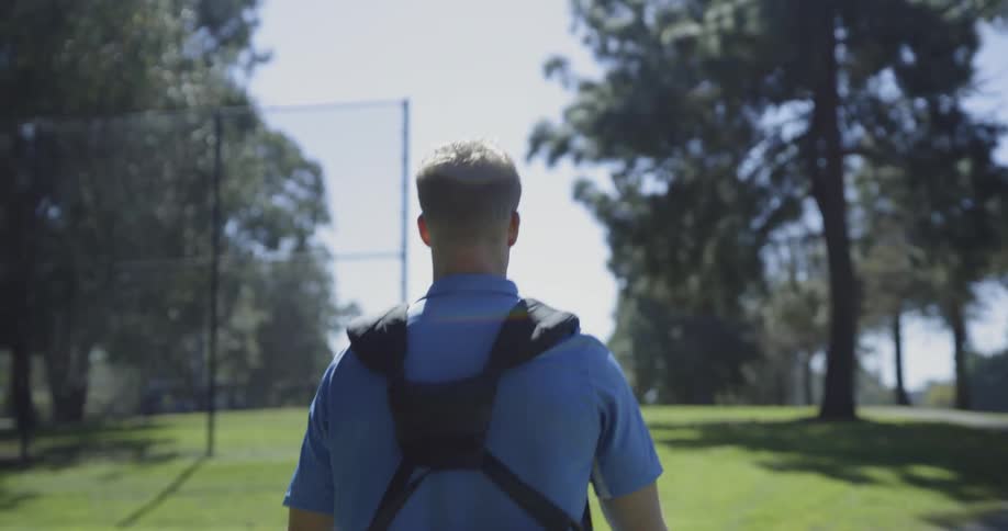 A golfer walks across a golf course carrying his clubs