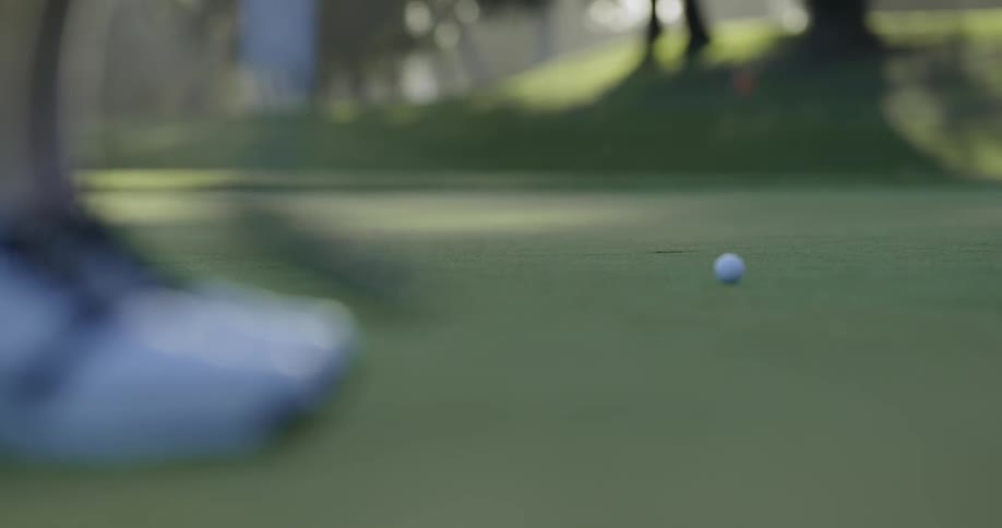 A golfer putts and sinks the ball