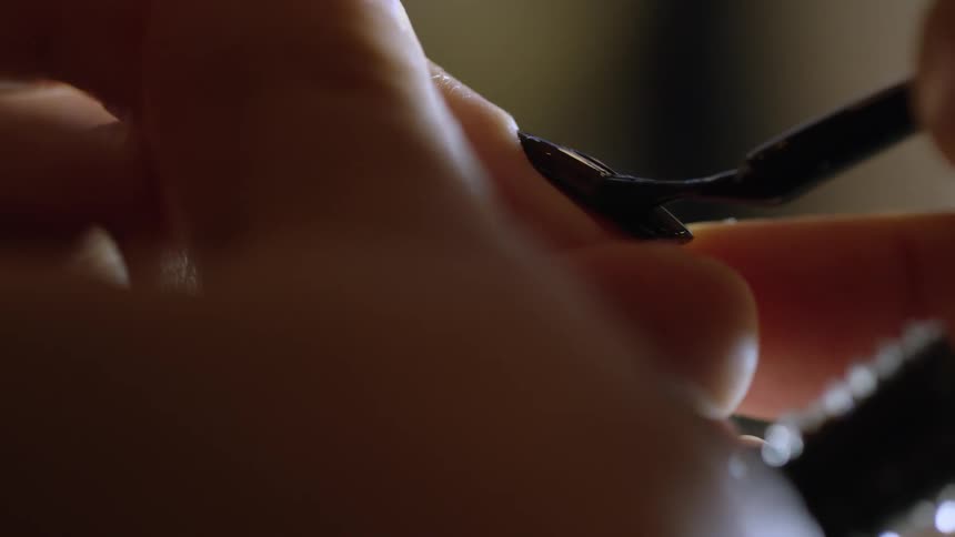A fingernail is painted a dark color