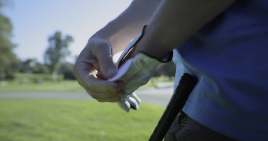 Man puts on glove and prepares to golf