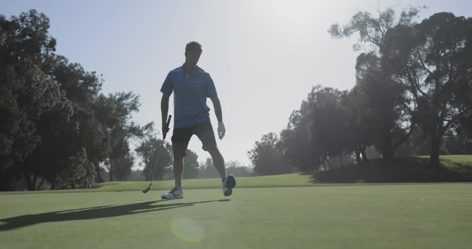 Golf player uses a club to hit the ball into the hole on a course