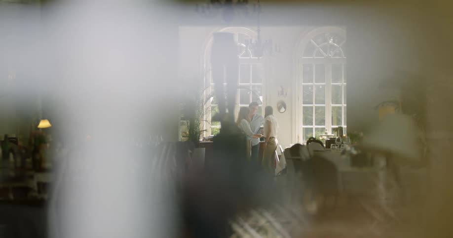 A formal banquet is set up as people talk next to large georgian windows