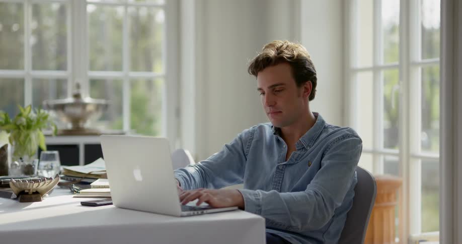 Man sitting at the table uses laptop in a room