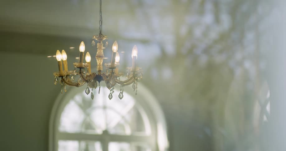 A golden chandelier with windows in the background