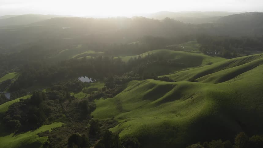 Lakes dot rolling green hills that border mountains