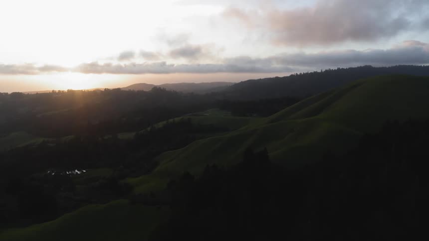 The sun is setting over a hill lined landscape