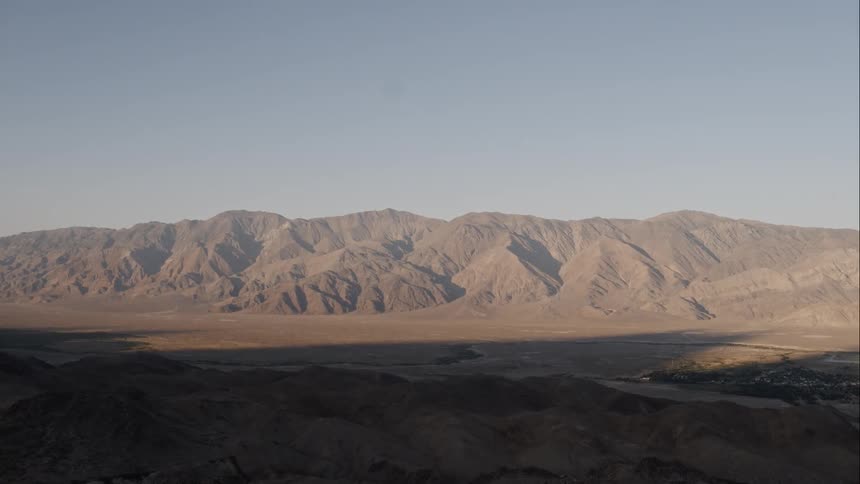 Flat land in the desert gives way to tall mountains