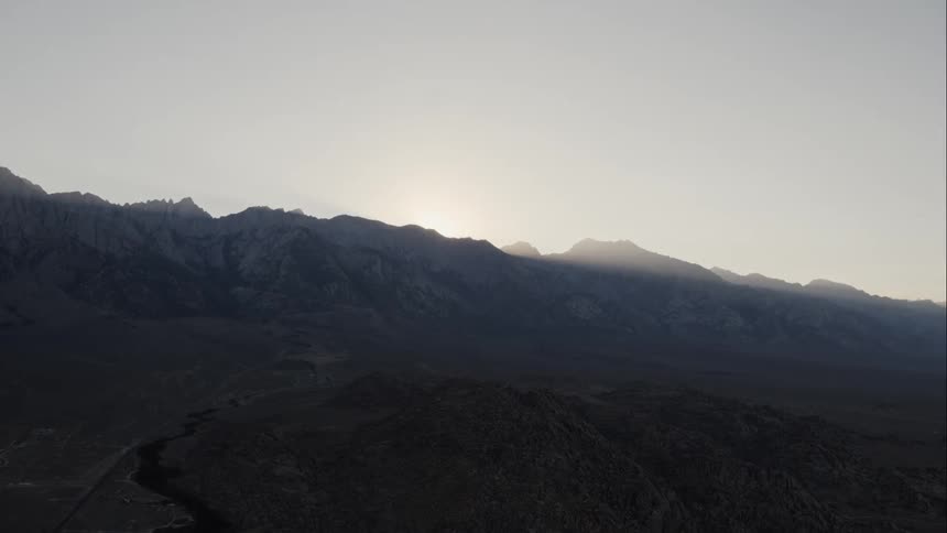 The sun rises behind the mountains