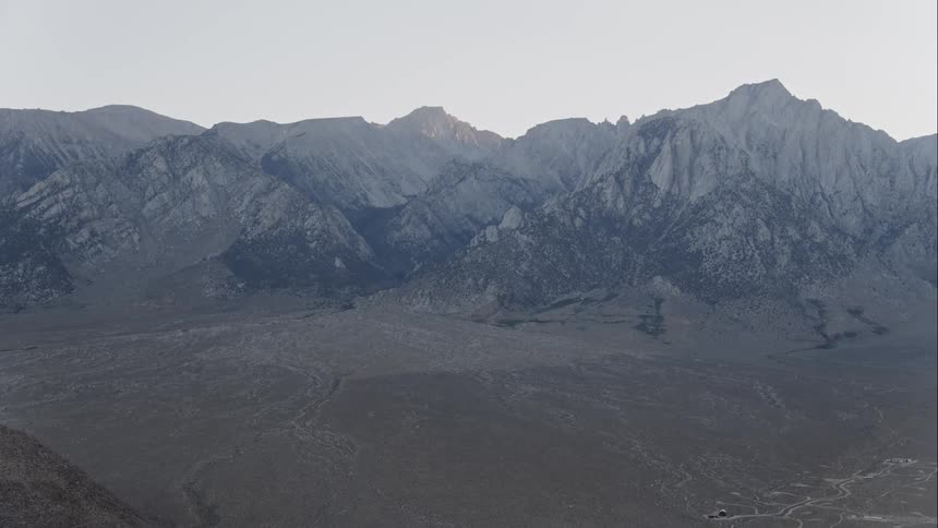 From high above the ground an enormous range of mountains can be seen standing tall against the sky