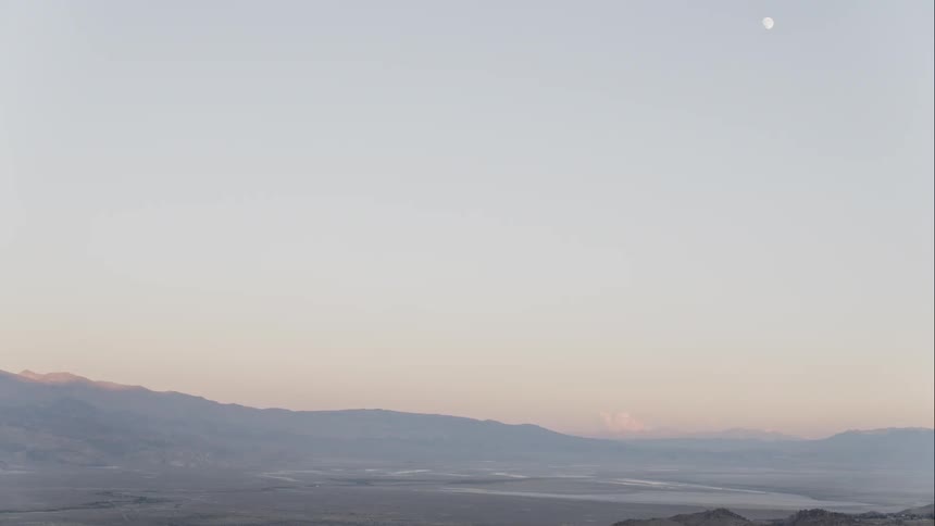 Panoramic view of deserted plain surrounde by mountains at sunset under the moon