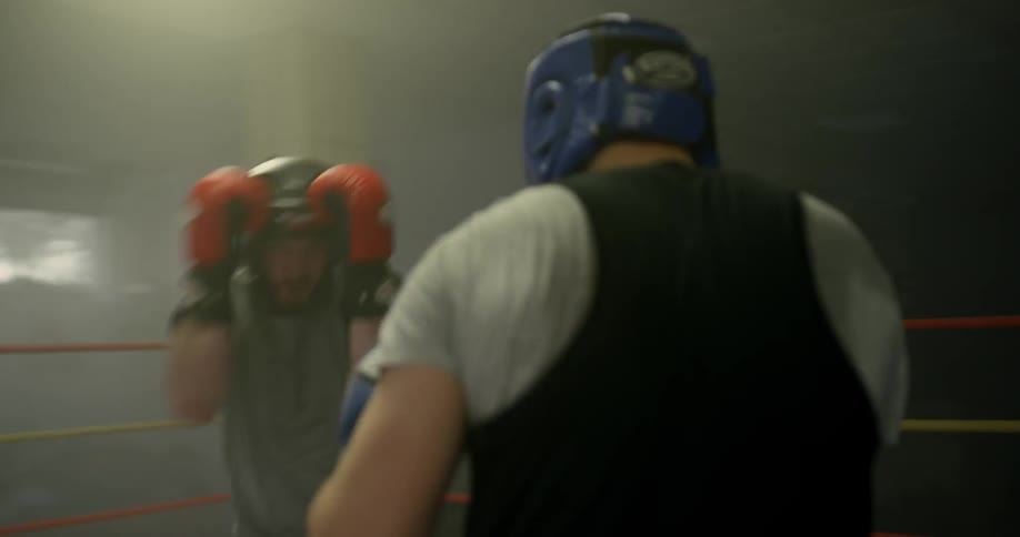 Two boxers train and hit each other in the boxing ring