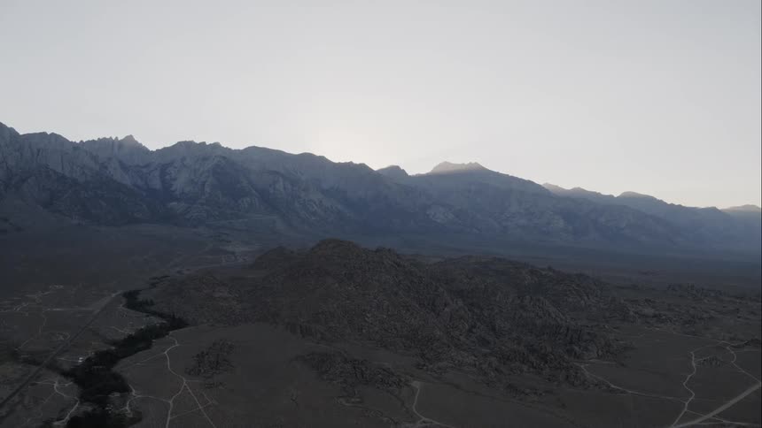 Aerial shot of a field in front of a mountains