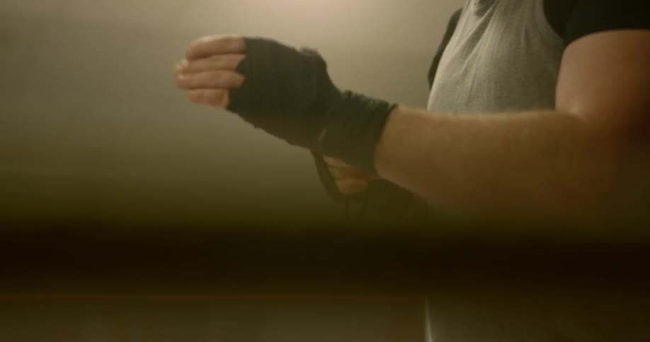 A boxer wraps black tape around his left hand