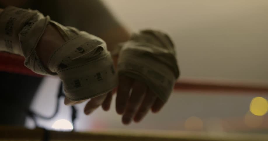 A person with taped hands hangs them over a rope