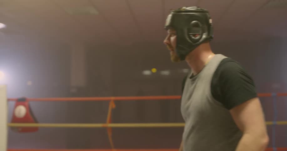 Boxer wearing headgear wipes sweat and takes a breather